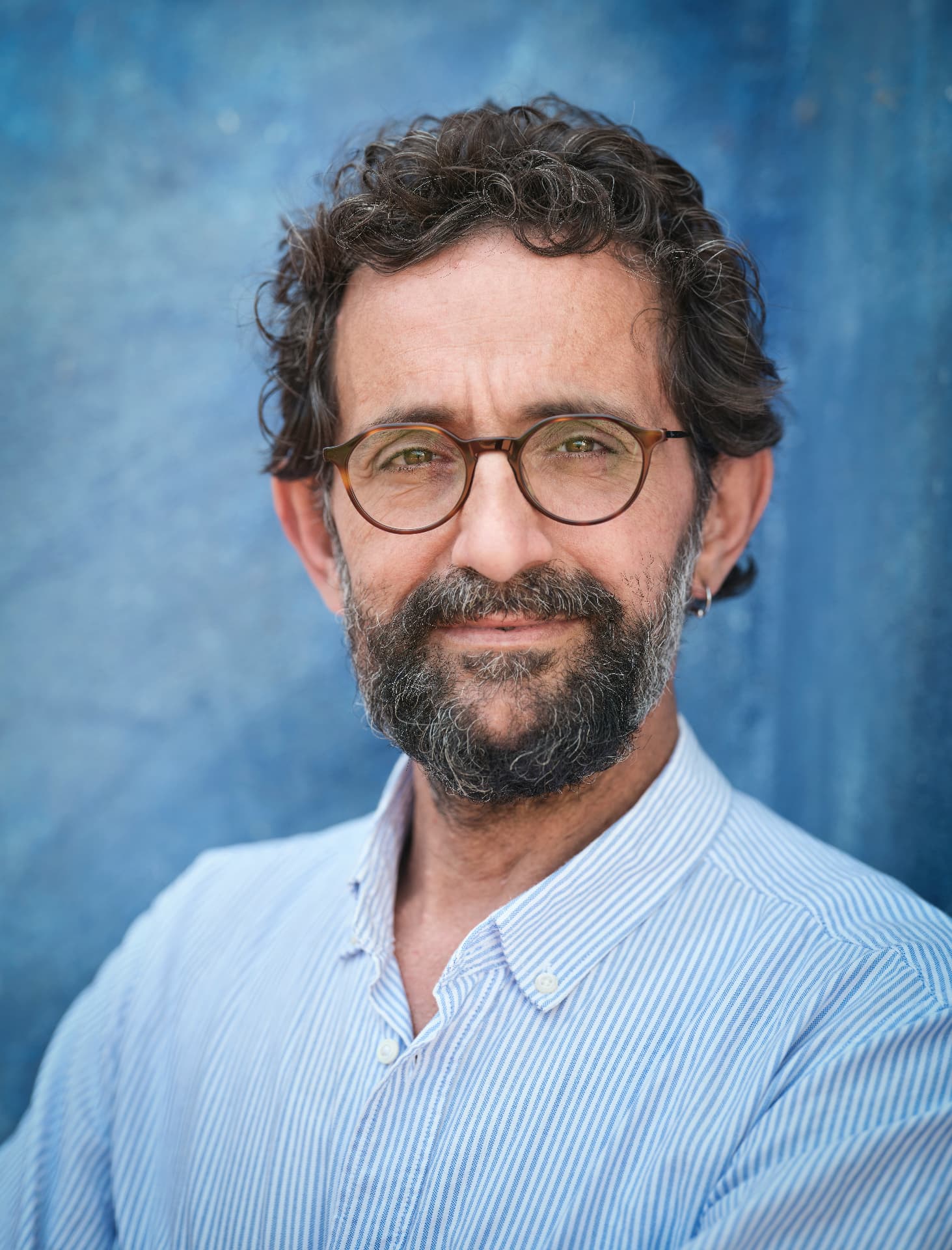 Portrait d'un homme souriant portant des lunettes sur fond bleu